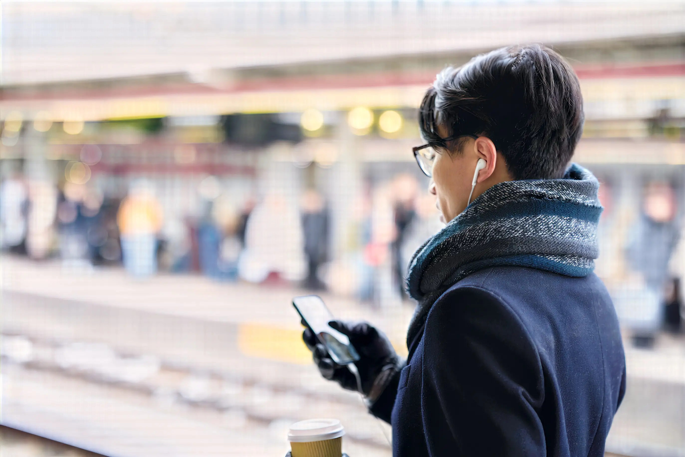 Kvinna står på tågperrong och kollar i sin mobil