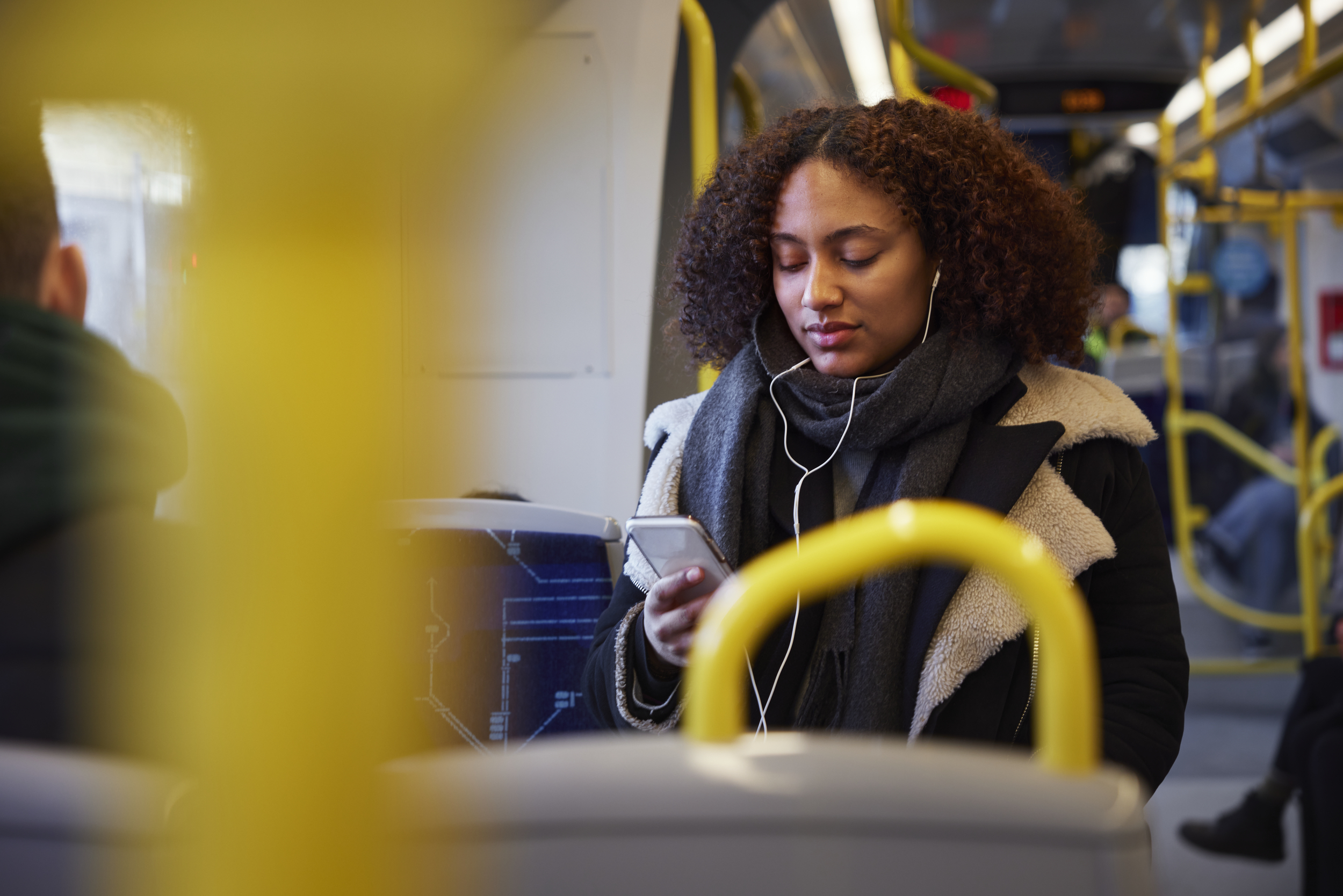 Kvinna som sitter på en buss och tittar i telefonen