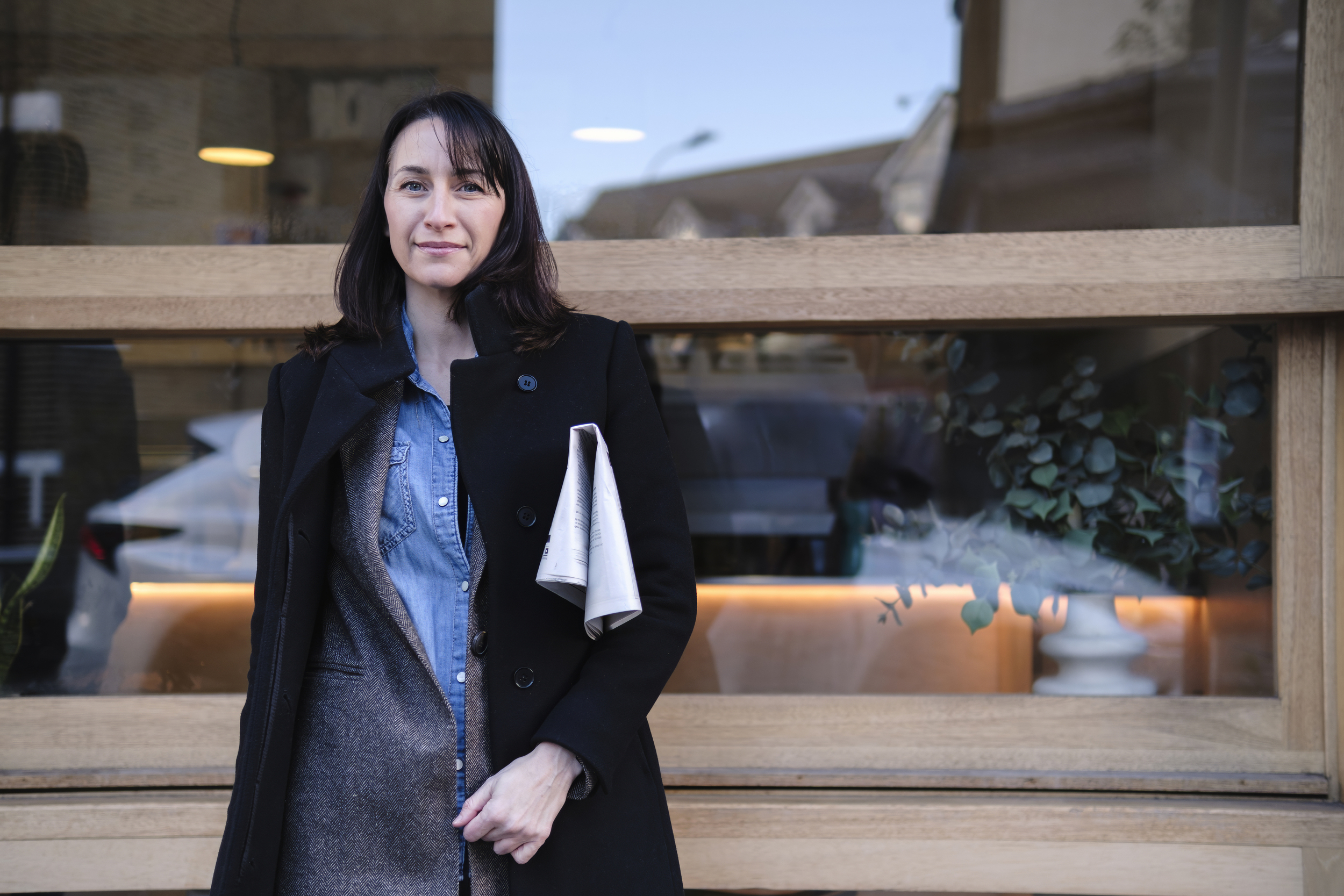 Kvinna står med tidning vikt under armen