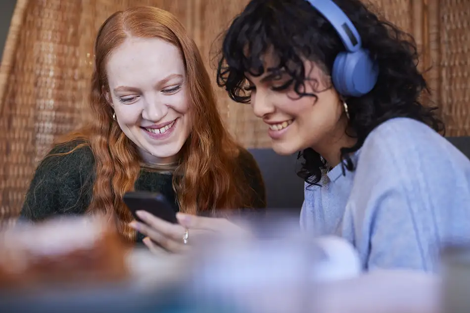 Två personer sitter nära varandra och tittar på en mobiltelefon.