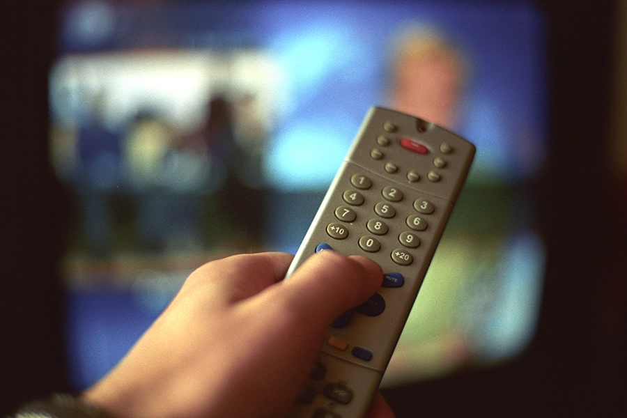 Hand som trycker på fjärrkontroll.