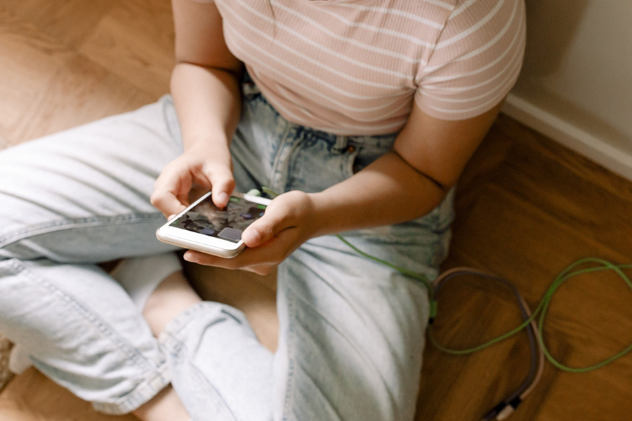 Tjej som sitter på golvet och tittar på mobilen