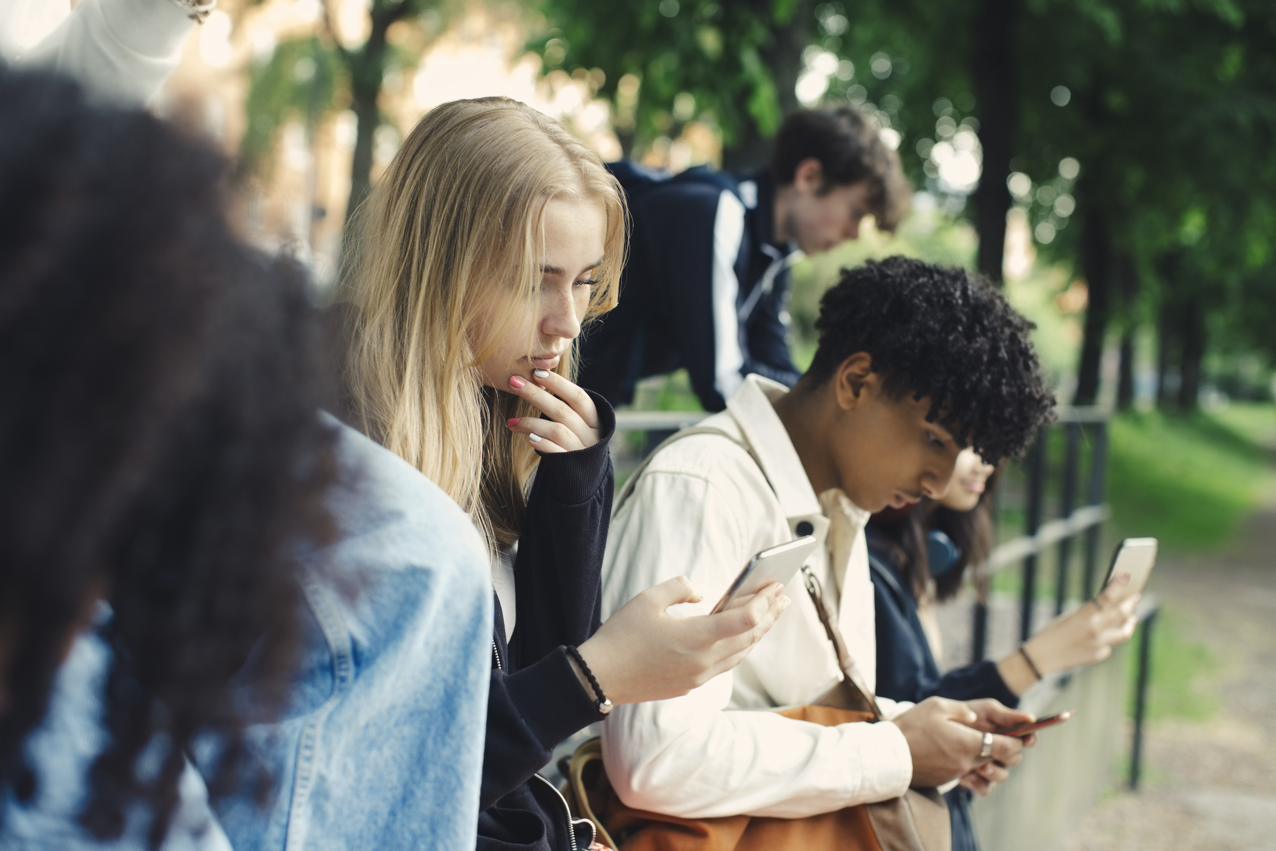 Ungdomar utomhus tittar på mobiler