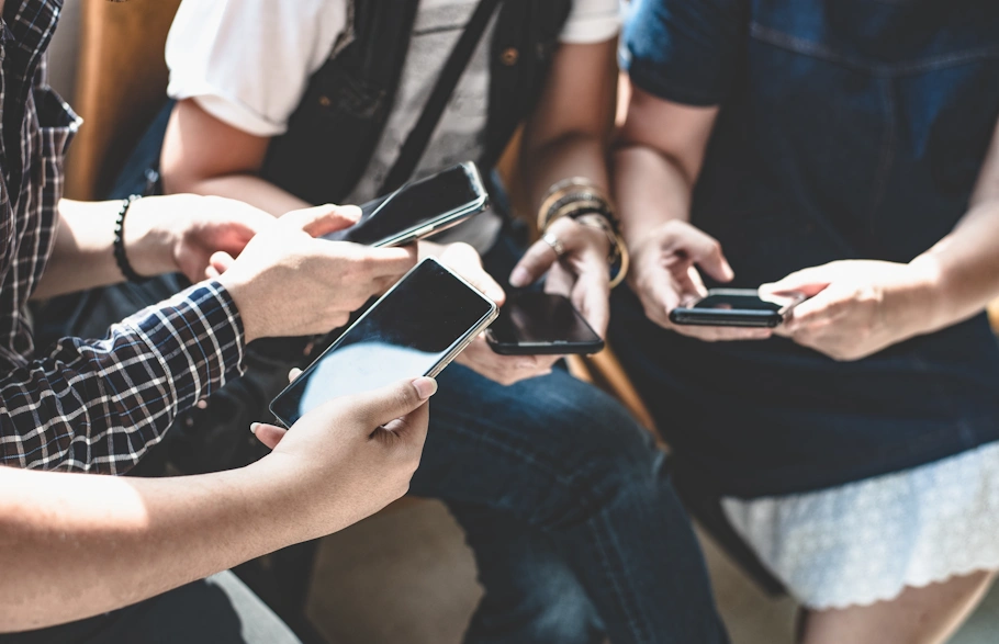 Fyra personer sitter tillsammans och håller varsin smartphone i händerna.
